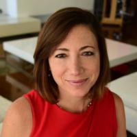 A person in a red dress is seated indoors, smiling.